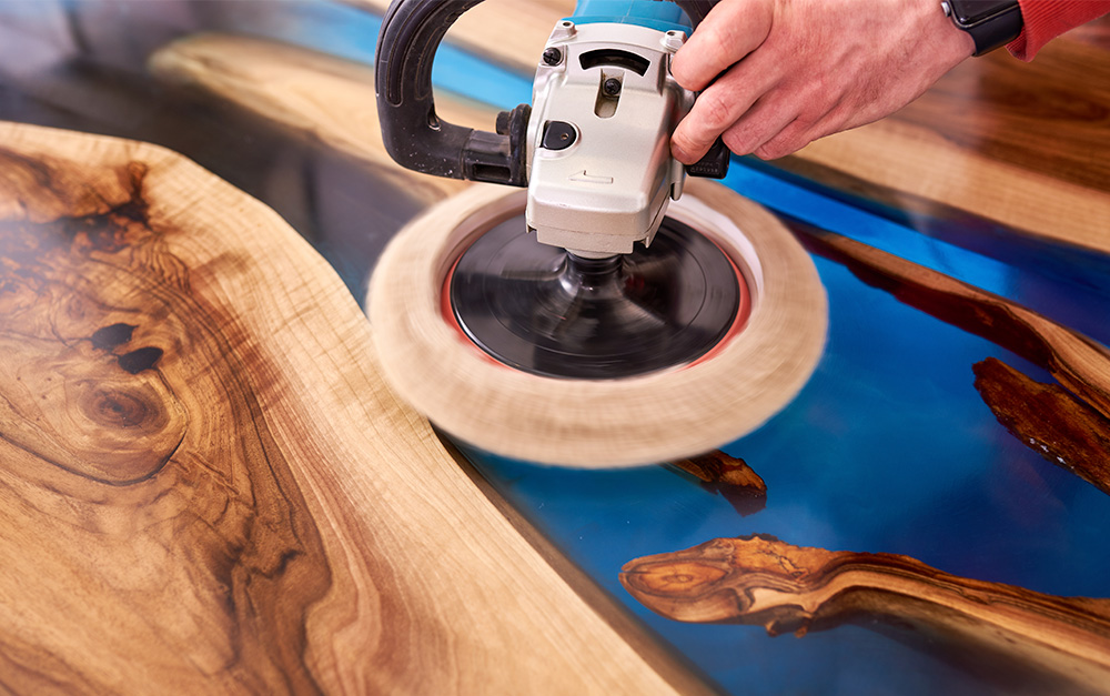 Mesa river table de madeira com resina pigmentada na cor azul sendo polida para alcançar um acabamento bonito