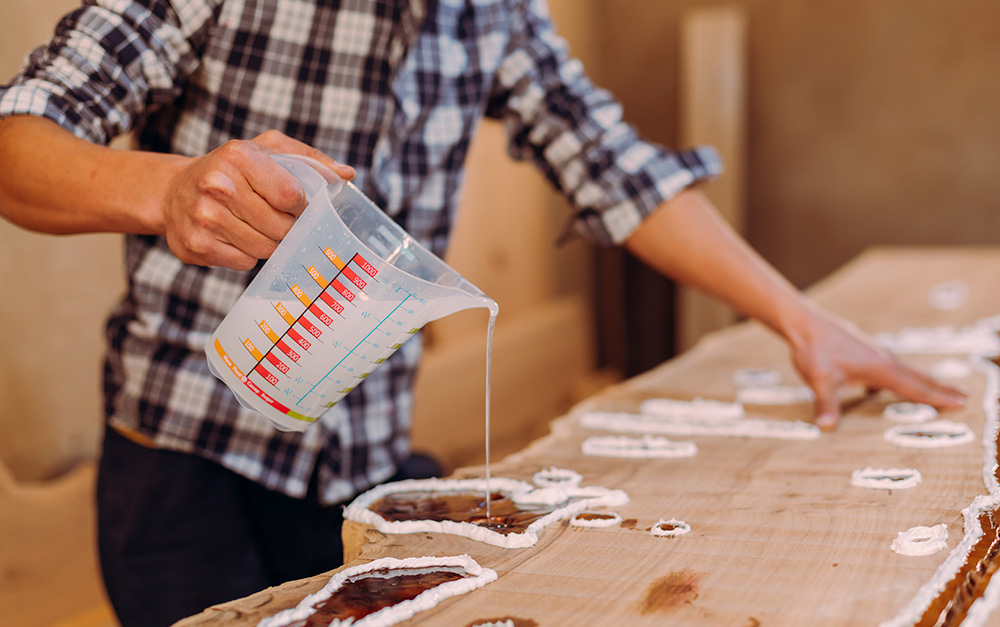 Trabalhador aplicando segunda camada de resina em uma mesa após ter verificado o ponto de gel