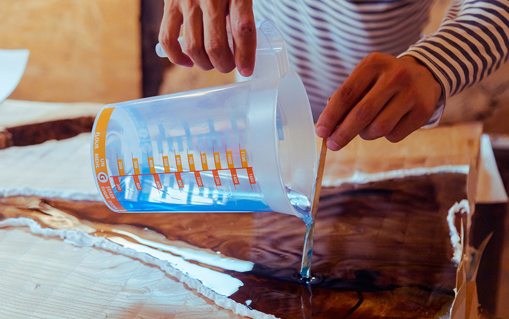 Pessoa aplicando a resina epóxi em uma superfície de madeira